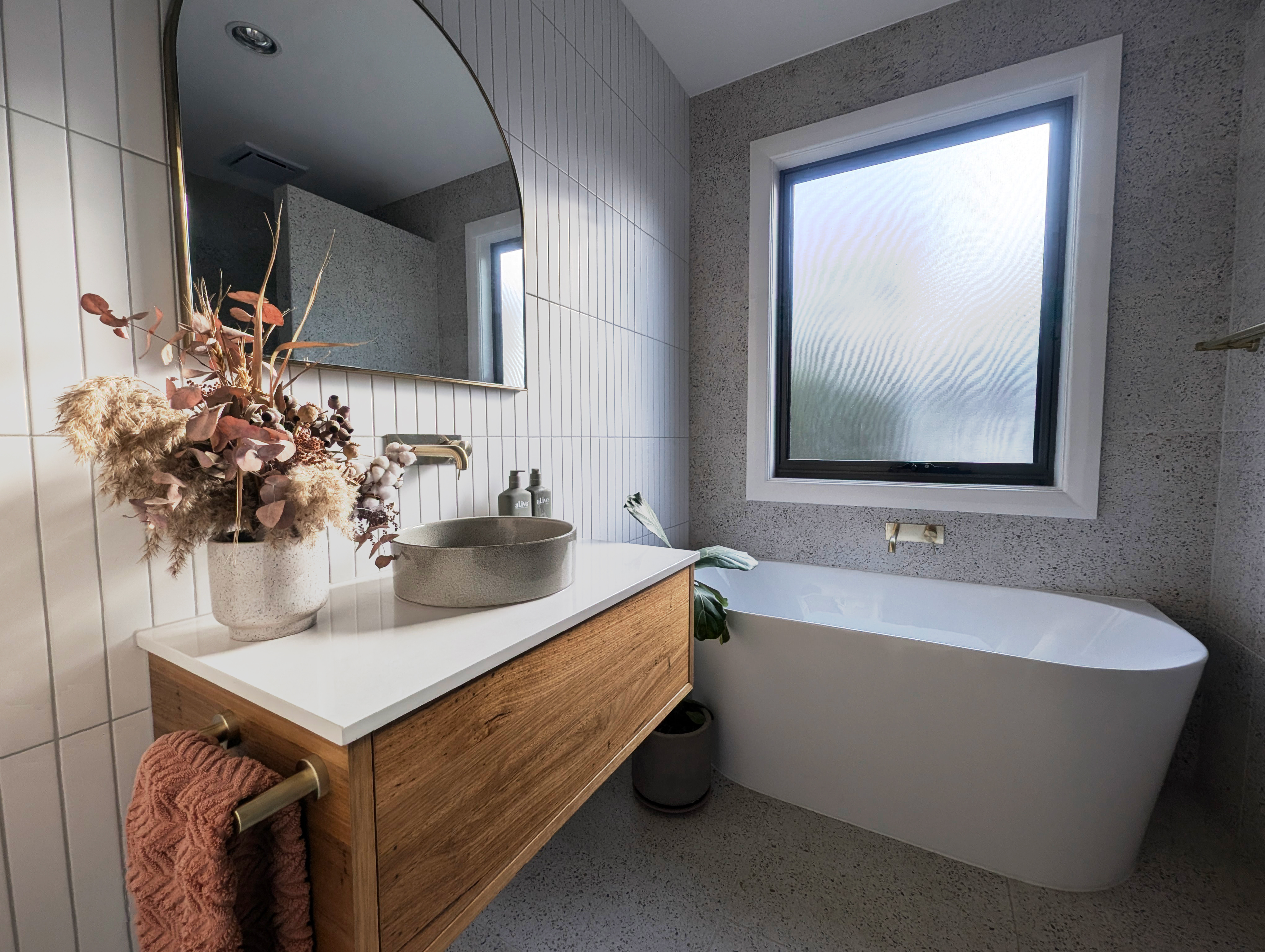 The Balhannah bathroom in full — floating vanity, freestanding bath and brass tapware over heated terrazzo-look floors