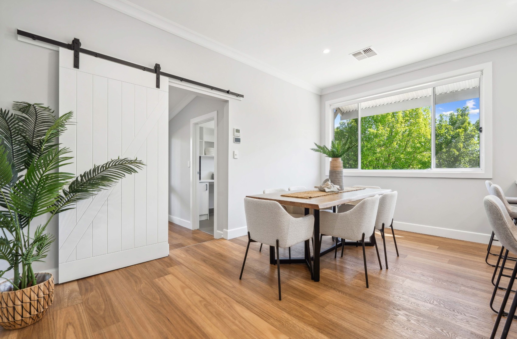 Dining room in the renovated Charleston home, with sliding barn door and a garden window behind the table