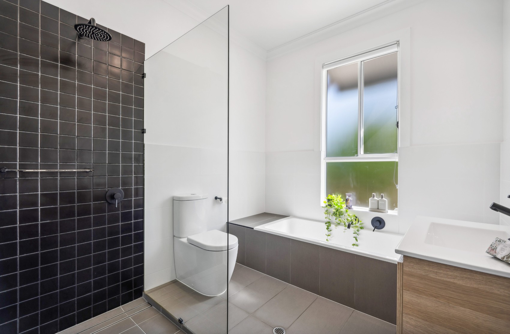 Charleston bathroom renovation — black-tiled shower beside the new built-in bath under the window