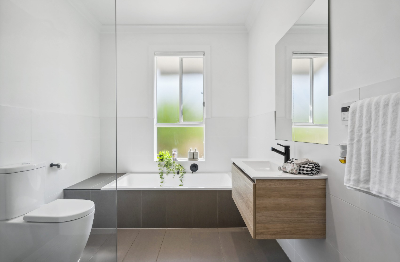 Built-in bath with full-height grey tiling and floating timber vanity, part of the Charleston bathroom renovation