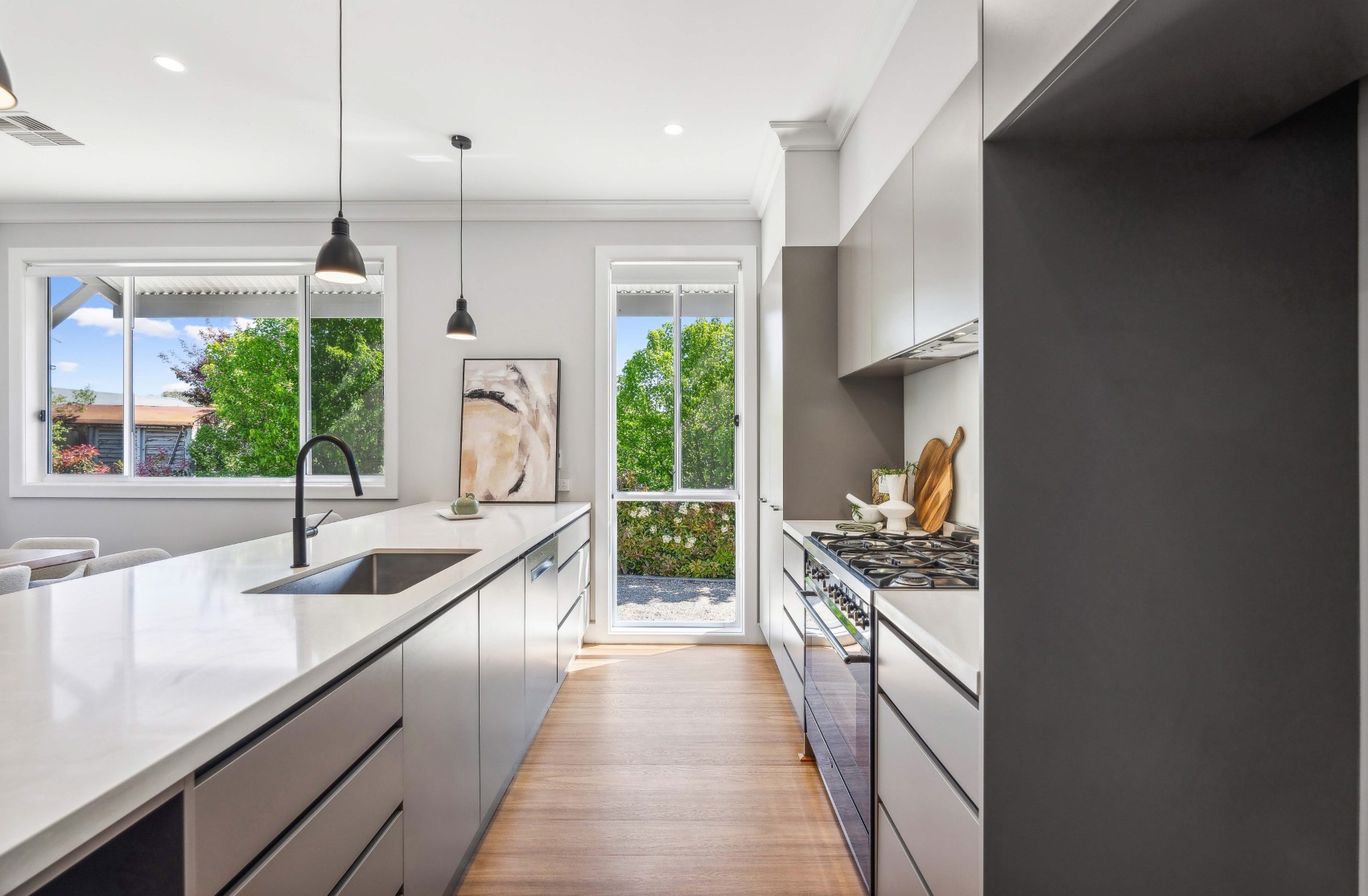 New galley kitchen for the Charleston renovation — stone island bench with undermount sink, black tapware and pendants, freestanding gas cooker