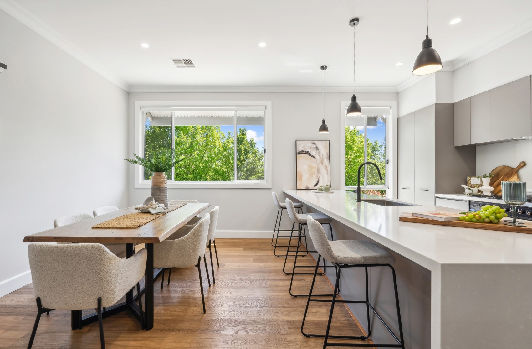 Renovated open-plan kitchen and dining at Charleston — new stone island with bar seating beside the timber dining table