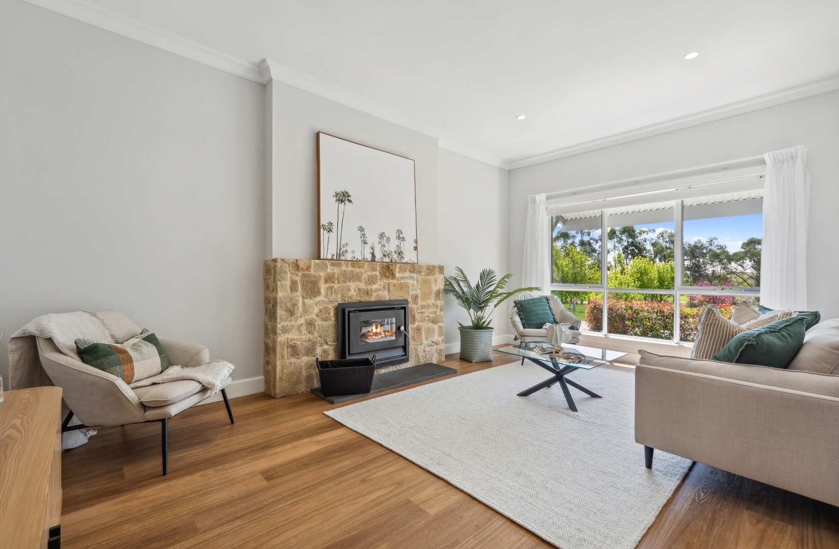 Living room in the renovated Charleston home — sandstone fireplace with slow-combustion heater and a picture window to the garden