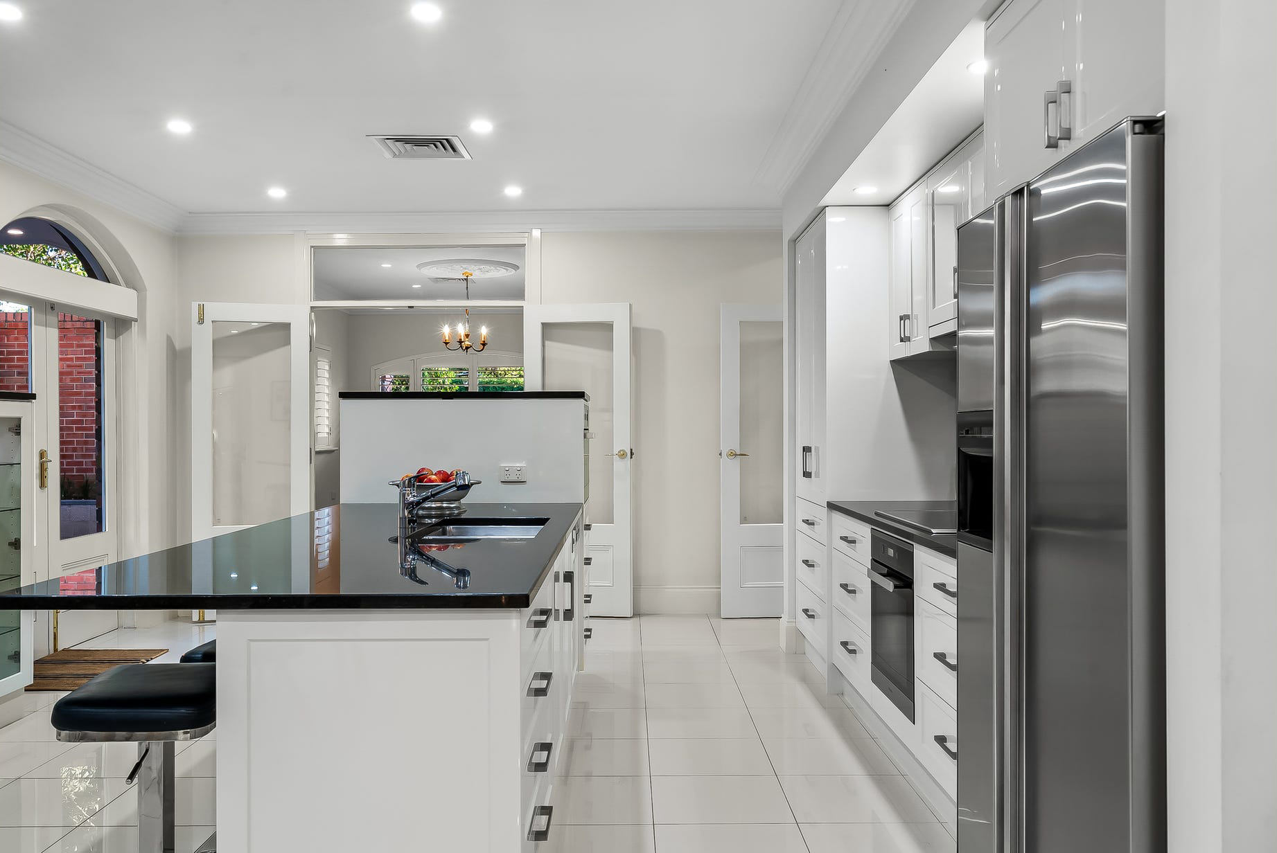 New Burnside kitchen — white cabinetry with black granite benchtops, stainless appliances and French doors to the courtyard