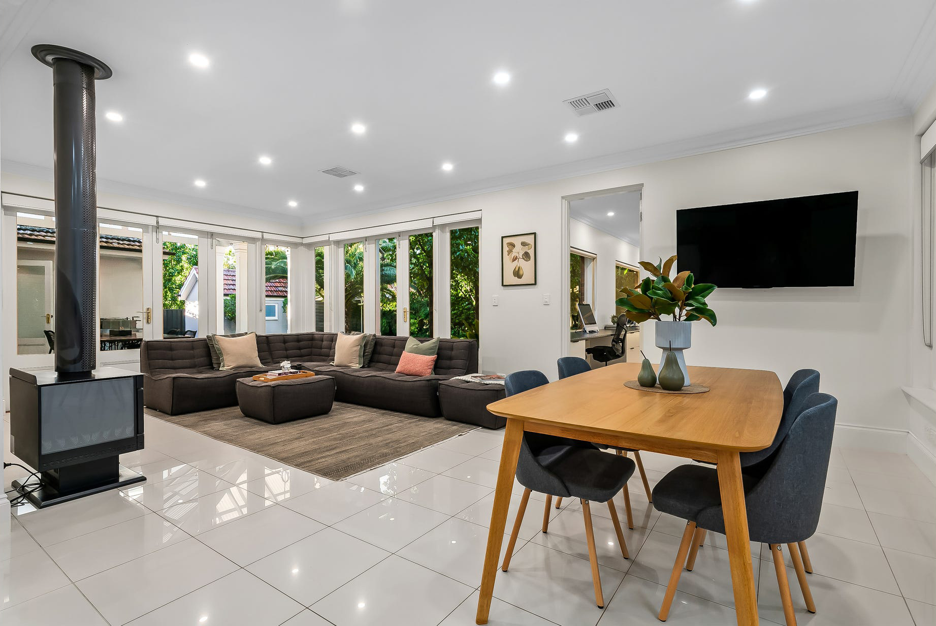 Family room off the new Burnside kitchen — modular lounge by the wood heater, bifold windows to the pavilion
