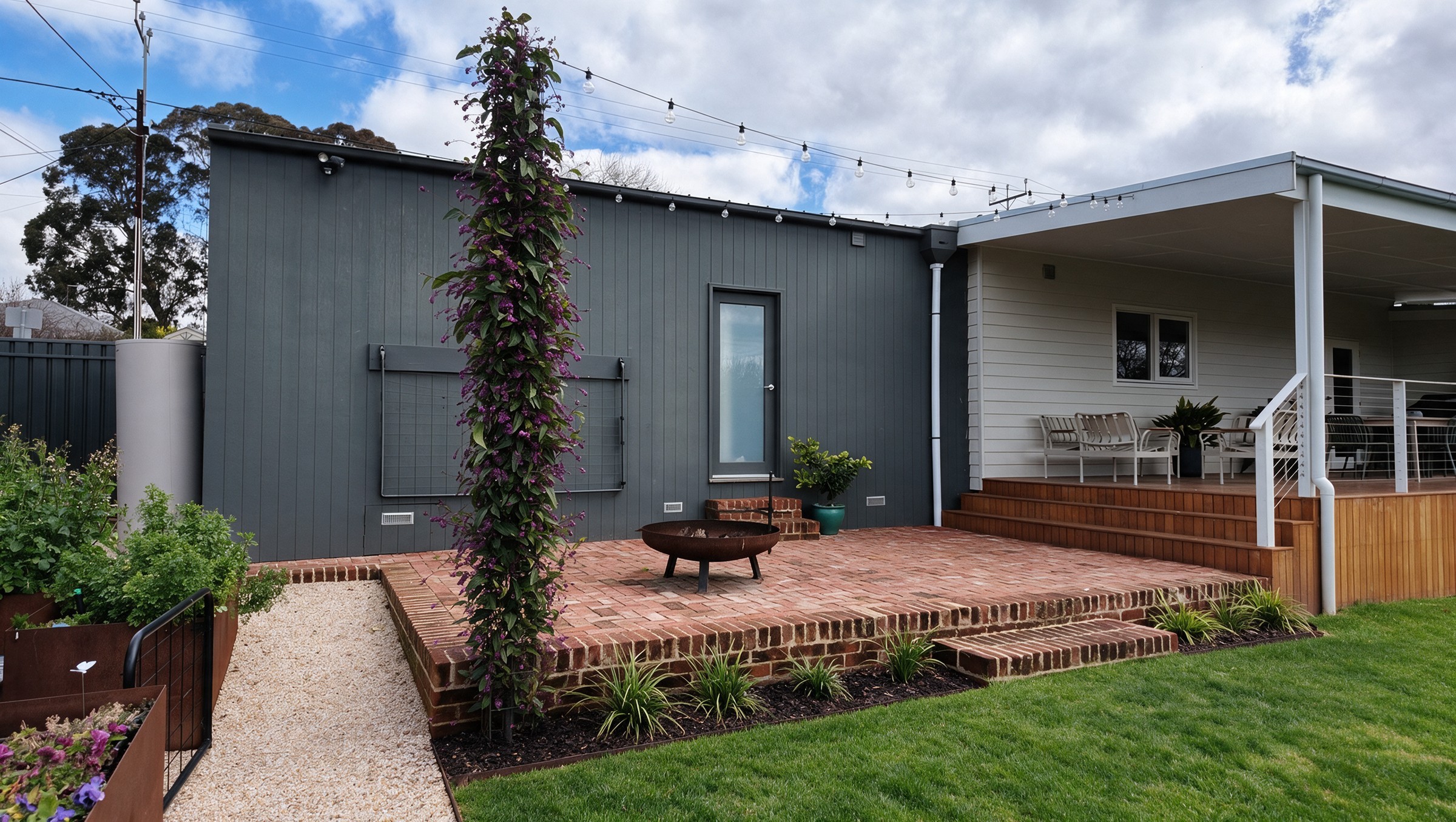 Recycled red brick terrace and fire pit between the charcoal extension and the verandah, with festoon lighting overhead
