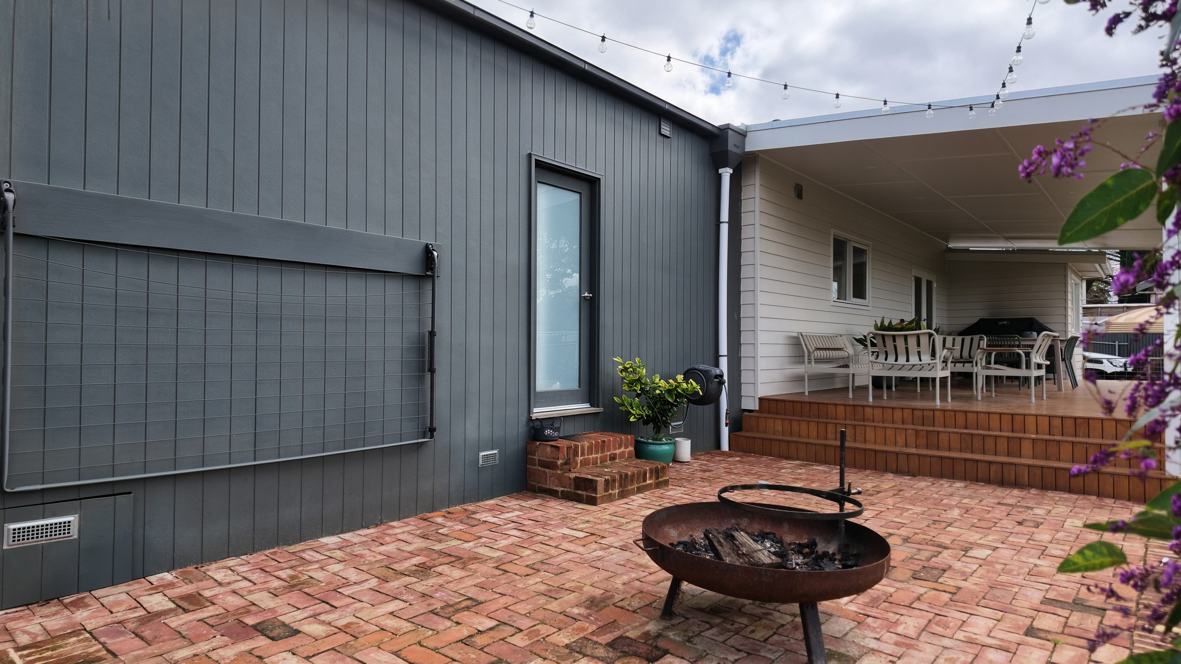 Sheltered courtyard between the extension and the deck, with the fire pit on recycled red brick paving