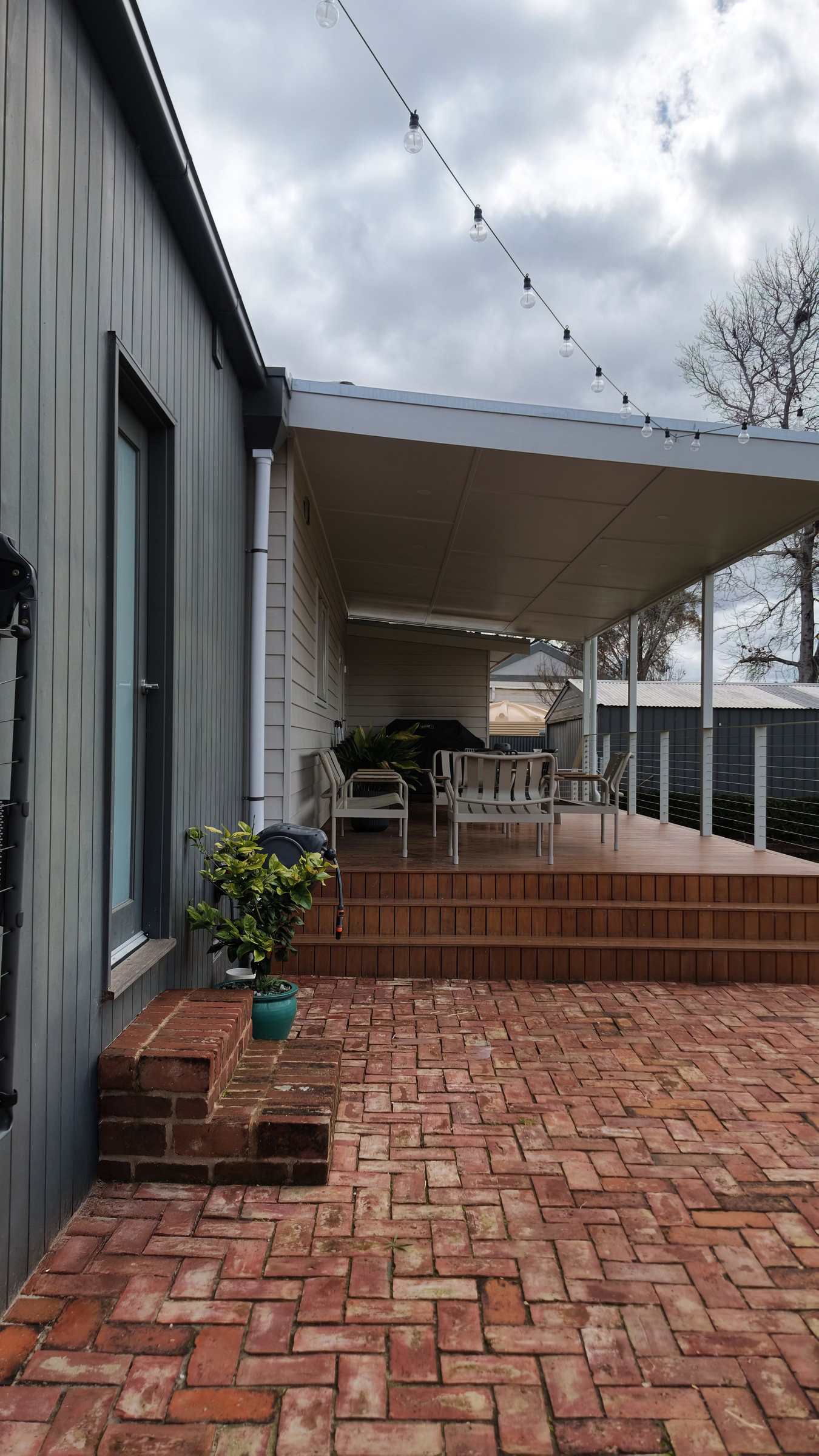 Recycled brick paving leading to the hardwood deck steps, the charcoal extension wall on the left