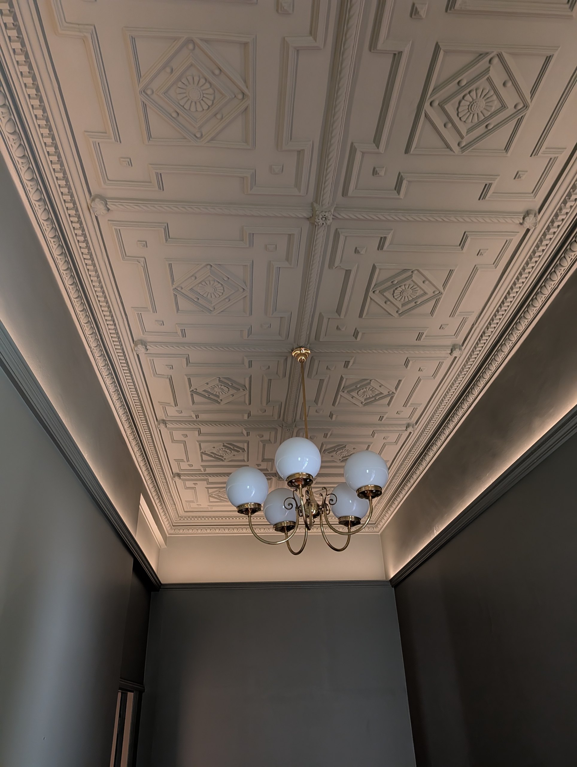 Ornate ceiling and brass chandelier lit from below by LED strip lighting concealed on a timber moulding