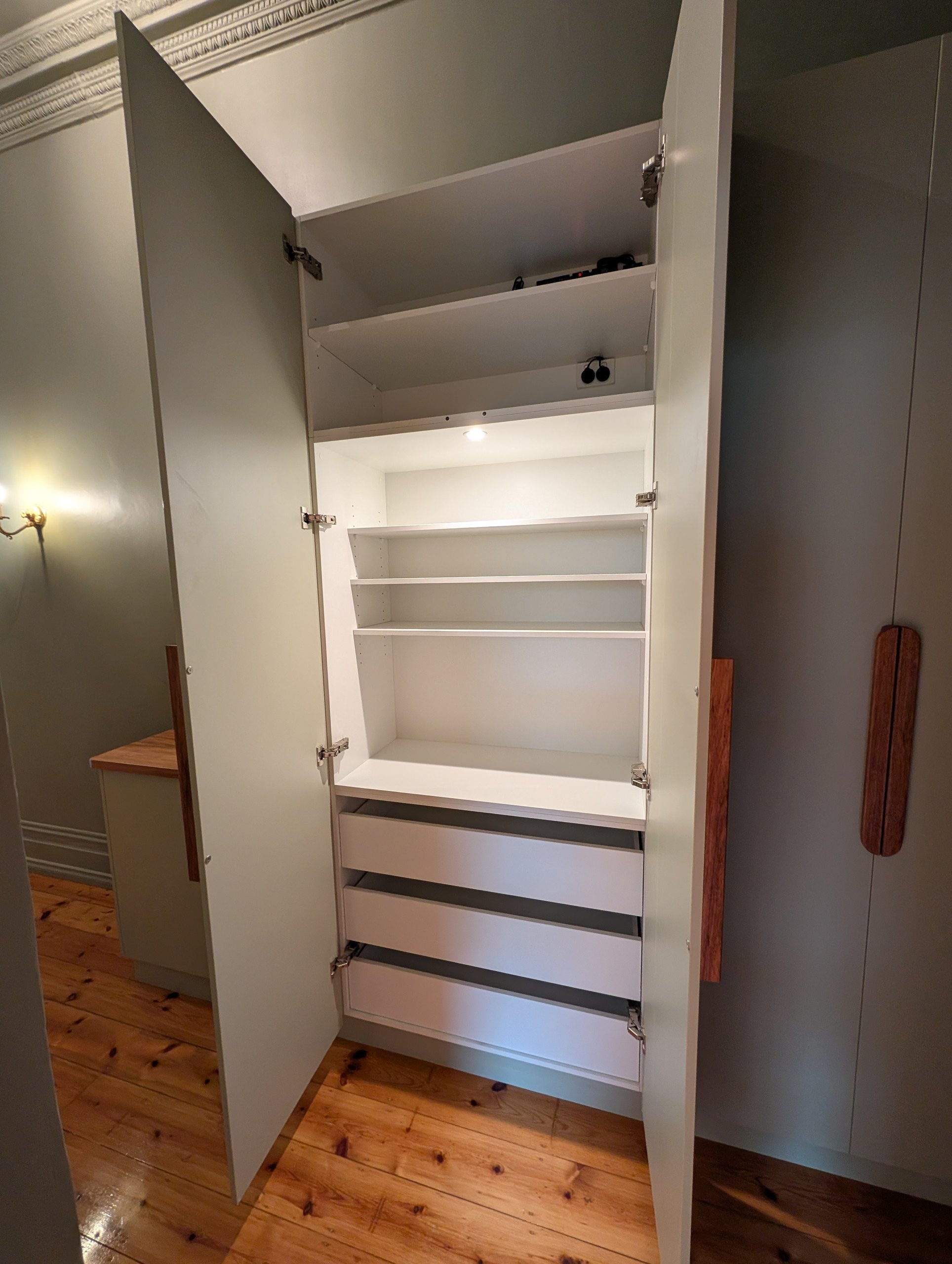 Hallway cupboard doors open to show white shelving inside