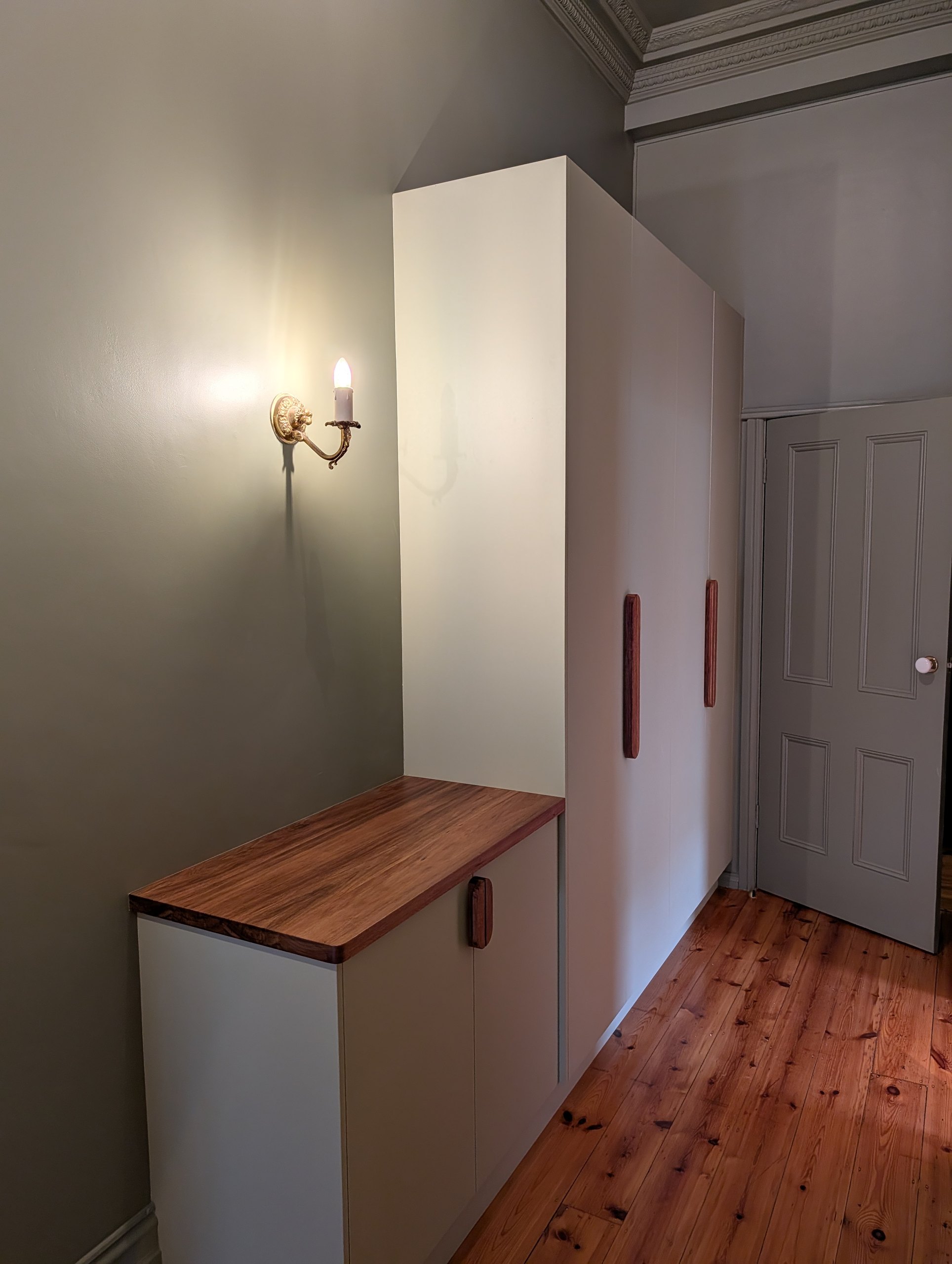Full-height hallway cupboards painted green to match the walls, with timber pull handles