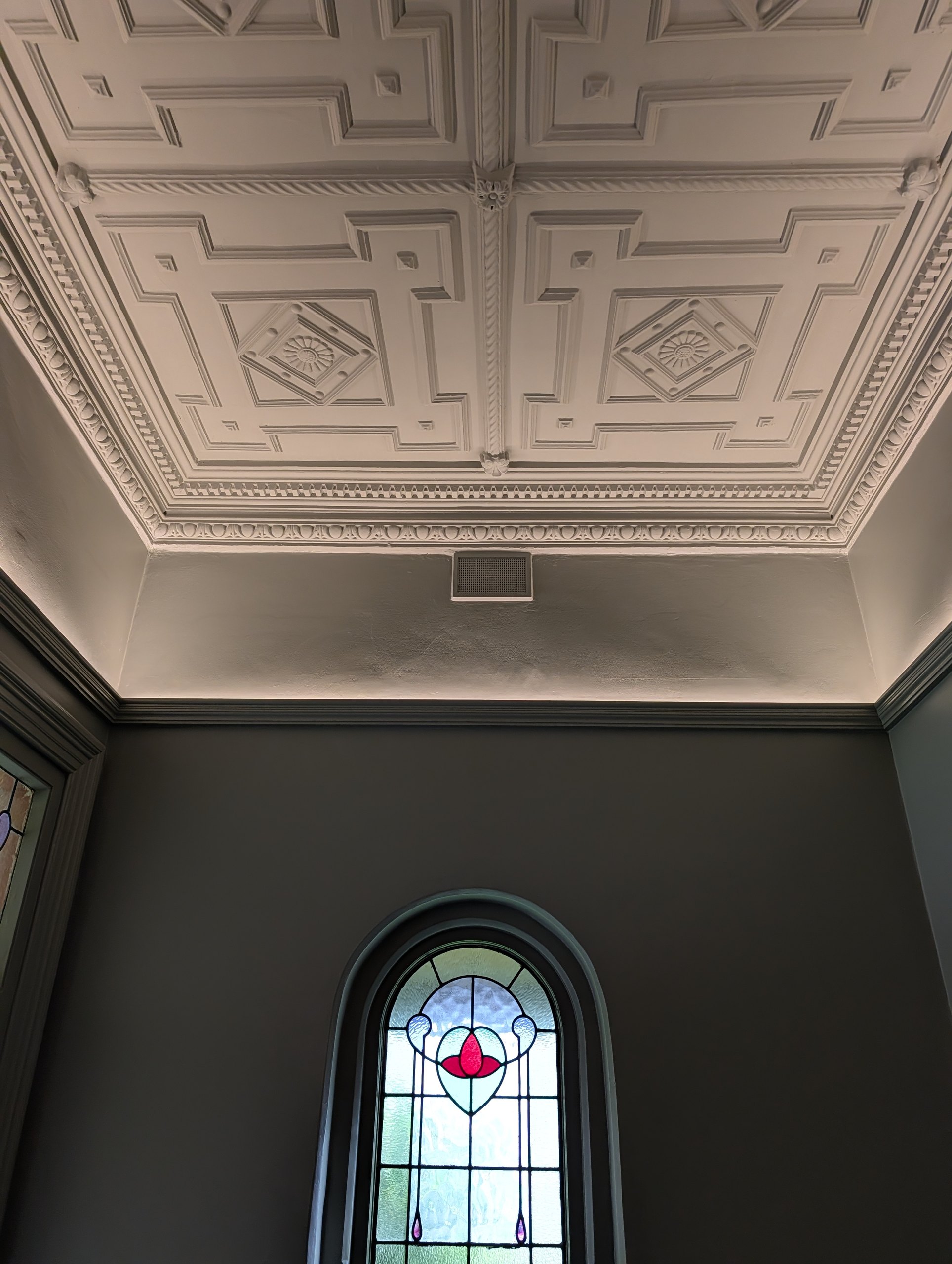 Stained glass fanlight and ornate ceiling washed by concealed LED lighting above the picture rail
