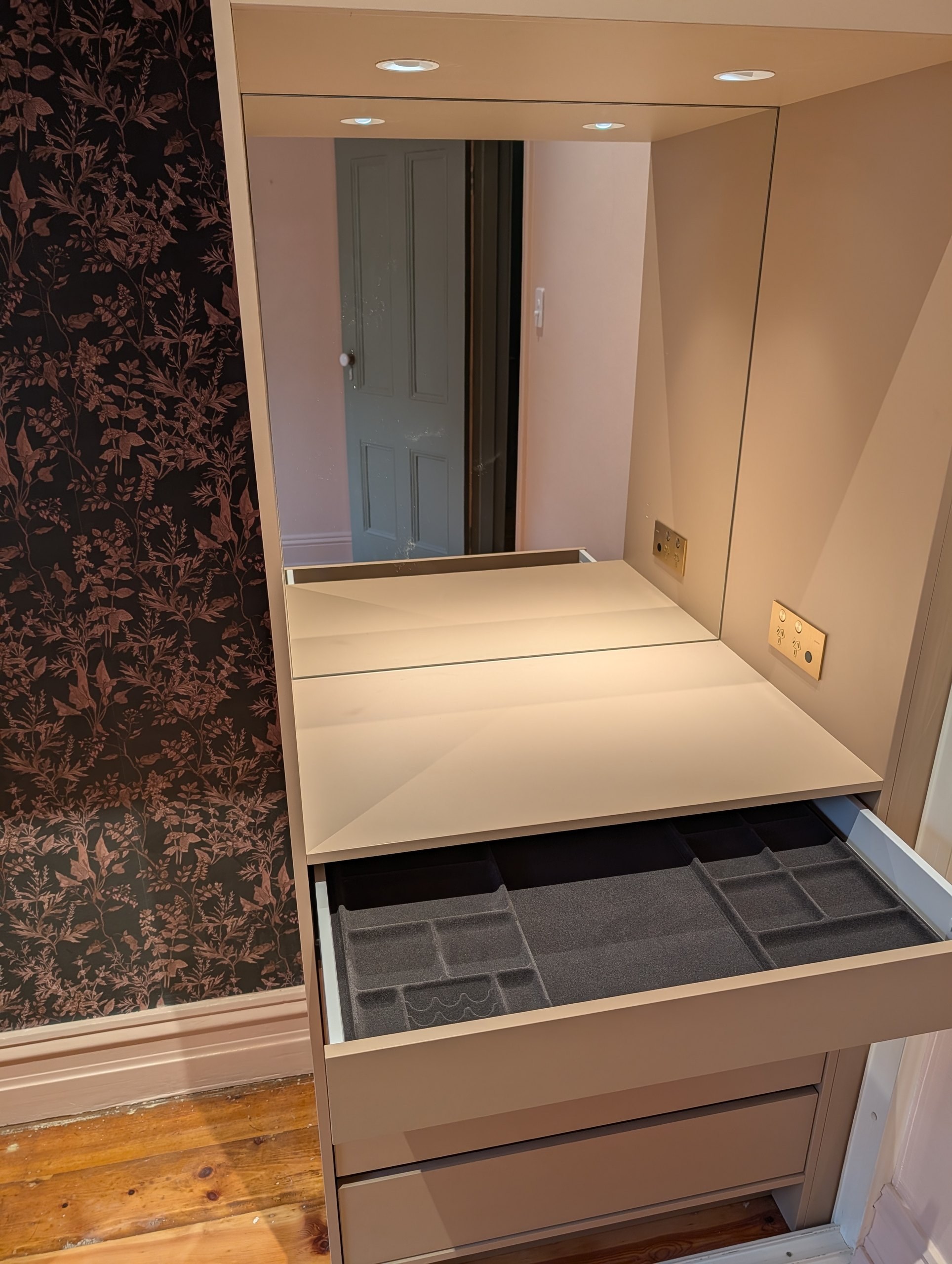 Makeup station inside the robe with mirror, downlights, brass power outlets and a fitted jewellery drawer
