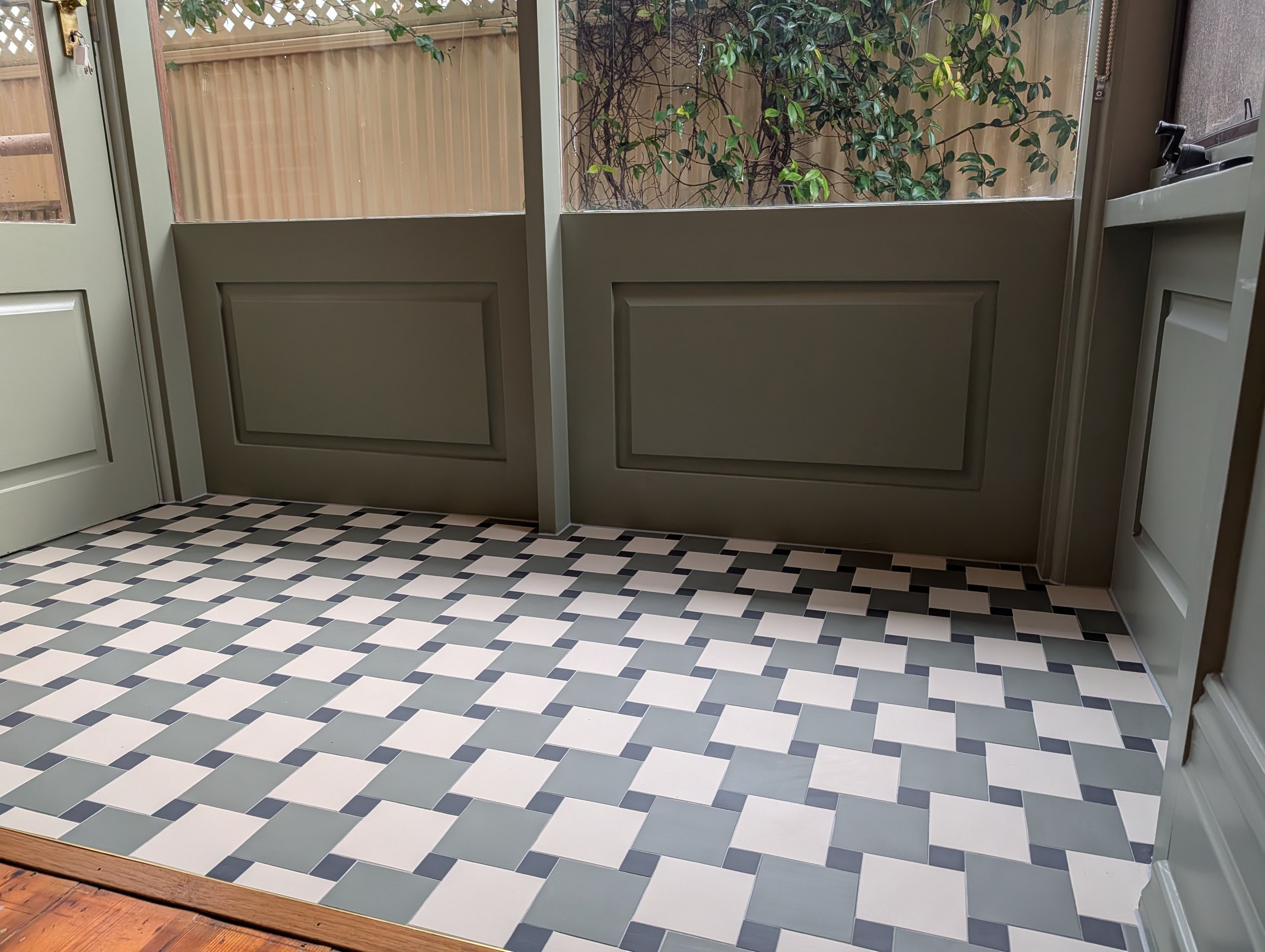 Sunroom side entry with green, blue and white pinwheel floor tiles against the panelled walls
