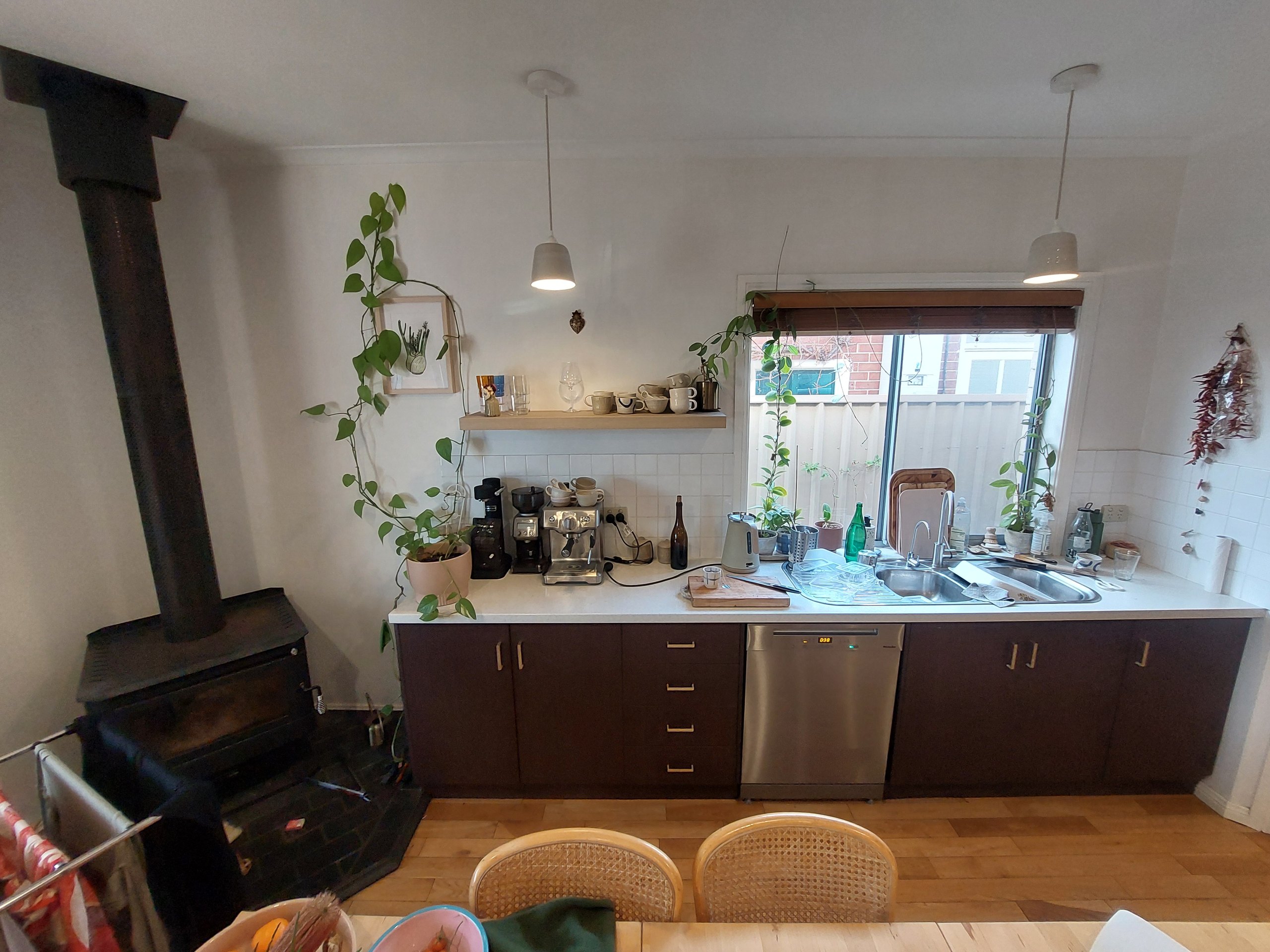 The Kilkenny kitchen before work started: a short run of dark cupboards, a wood fireplace in the corner and a single-glazed window