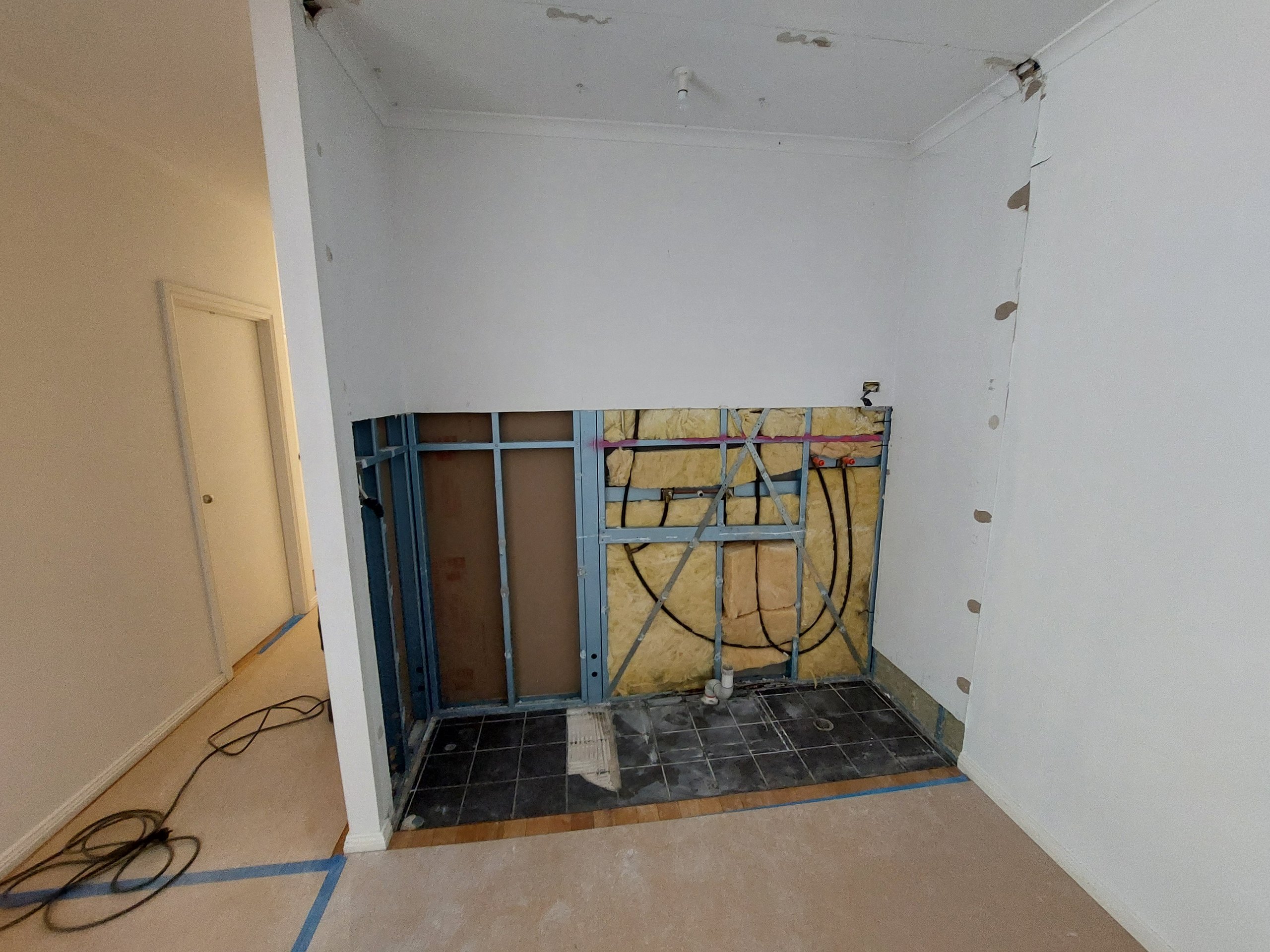 Corner of the kitchen after the wood fireplace was removed, showing the frame, new plumbing and the hearth area