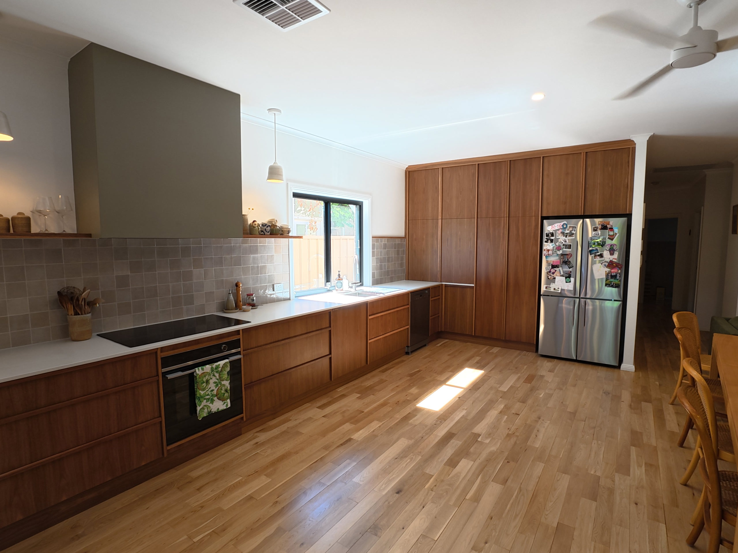 Timber kitchen with a long bench run, pantry wall and fridge, on polished hardwood floors