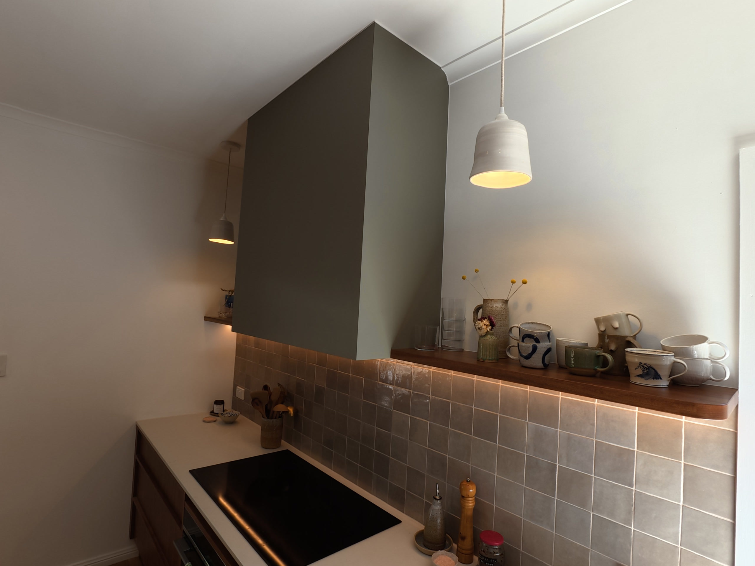 Rangehood, pendant light and timber shelf above the tiled splashback