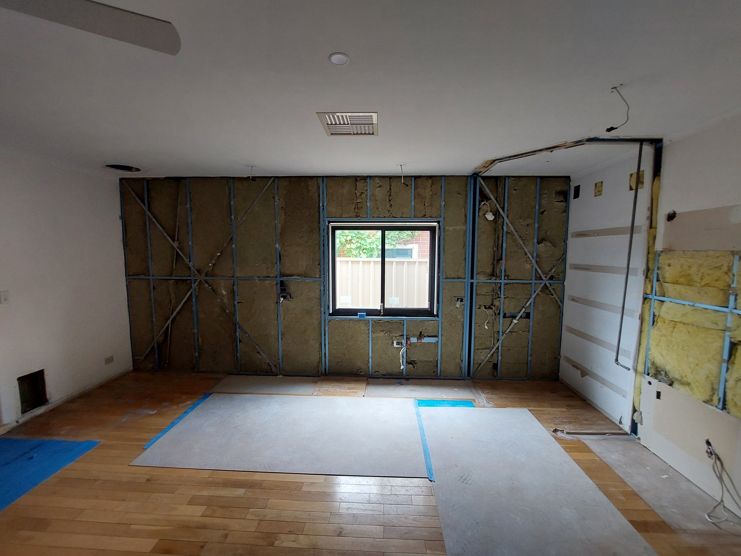 Kitchen stripped back to the timber frame and insulation, with the floor protected and the old kitchen removed